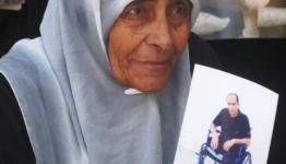 أم تحمل صورة أبنها الذي اصيب بإعاقة داخل السجون