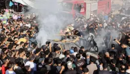 غزيون يتابعون نتائج غاترة اسرائيلية استهدفت مركبة