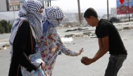 فتاتان فلسطينيتان تقدمان الحجارة لشاب لرشق جنود الاحتلال بمواجهات في نابلس