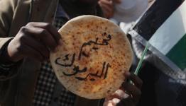 فلسطيني يرفع رغيف خبز كتب عليه مخيم اليرموك 