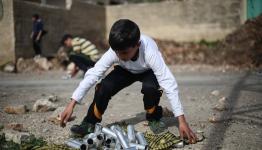 طفل فلسطيني يجمع قنابل الغاز الفارغة التي أطلقها جنود الاحتلال خلال المواجهات التي اندلعت في قرية كفر قدوم (أحمد طلعت)