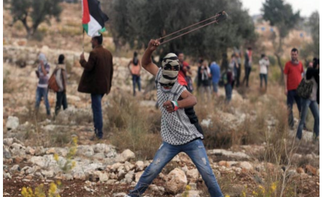 طفل فلسطيني يرمي حجر بمقلاع