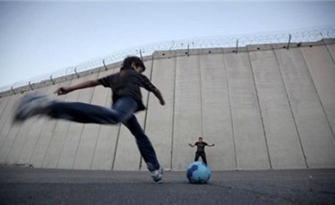 طفل فلسطيني يسدد الكرة على جدار الفصل العنصري 