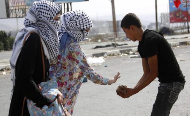 فتاتان فلسطينيتان تقدمان الحجارة لشاب لرشق جنود الاحتلال بمواجهات في نابلس