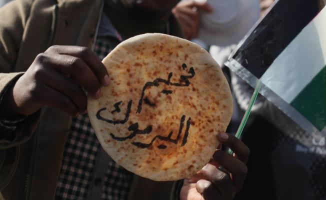 فلسطيني يرفع رغيف خبز كتب عليه مخيم اليرموك 