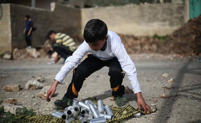 طفل فلسطيني يجمع قنابل الغاز الفارغة التي أطلقها جنود الاحتلال خلال المواجهات التي اندلعت في قرية كفر قدوم (أحمد طلعت)